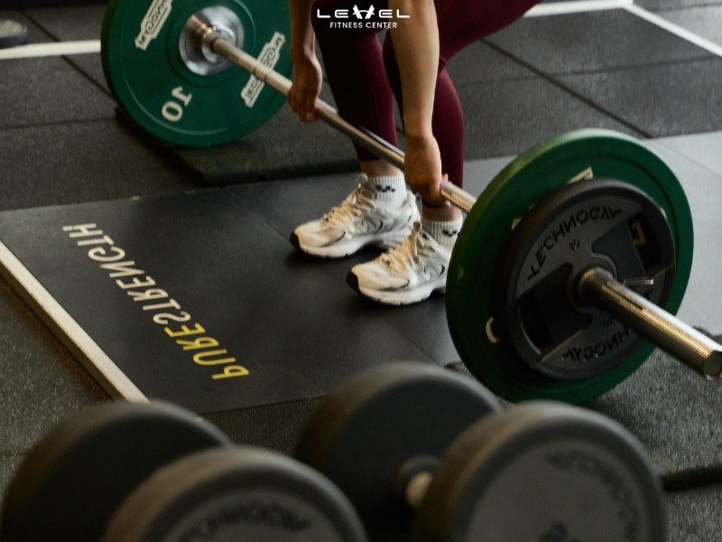 Các Phương Pháp Tập Gym Cho Người Mới Bắt Đầu: Hướng Dẫn Chi Tiết Từ A-Z Người đàn ông đang thực hiện bài tập squat với tạ đòn trong phòng gym