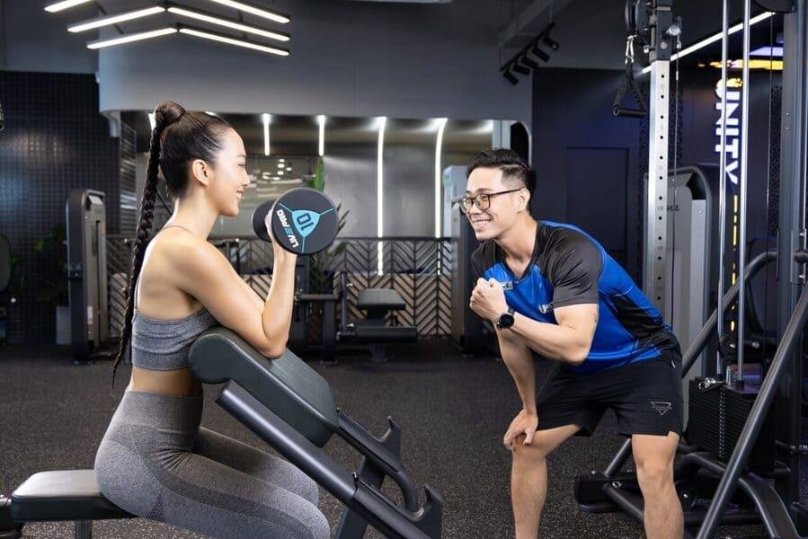 Huấn luyện viên đang hướng dẫn kỹ thuật tập gym đúng cho phụ nữ mới bắt đầu, tránh chấn thương