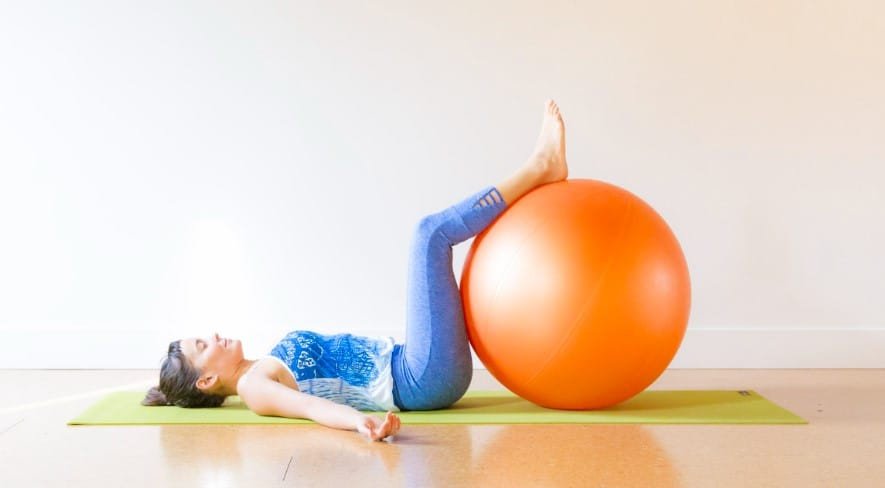 Người tập sử dụng bóng hỗ trợ trong tư thế Legs-up-the-Wall Pose của Iyengar Yoga