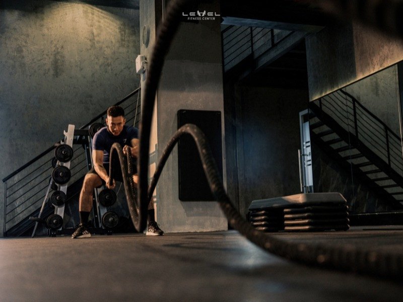 Người tập gym buổi tối với tạ đơn, tập trung cao độ